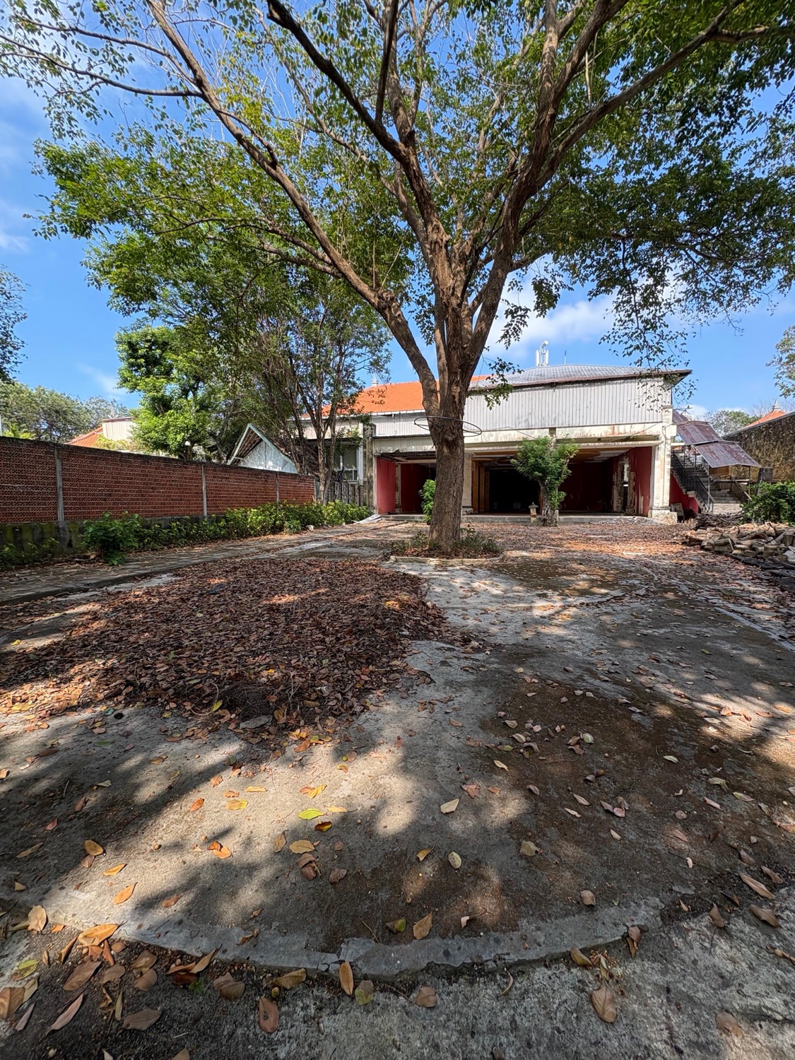 The Block E site as it stands — bare ground beneath mature trees